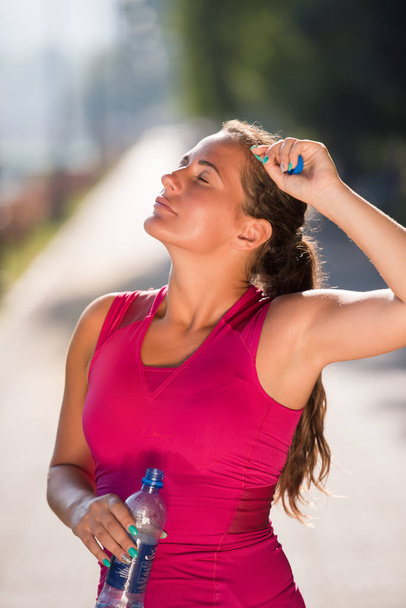 Athlète femme boire de l'eau d'une bouteille après avoir fait du jogging dans la ville par une journée ensoleillée
 - Photo, image