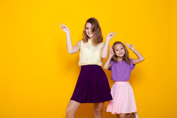 two girls in colored dresses laugh show fingers - Photo, Image