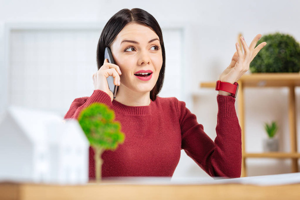 Emotional young woman using gestures while talking on the phone - Foto, imagen