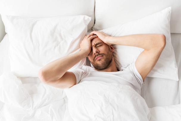 man in bed at home suffering from headache - Fotoğraf, Görsel