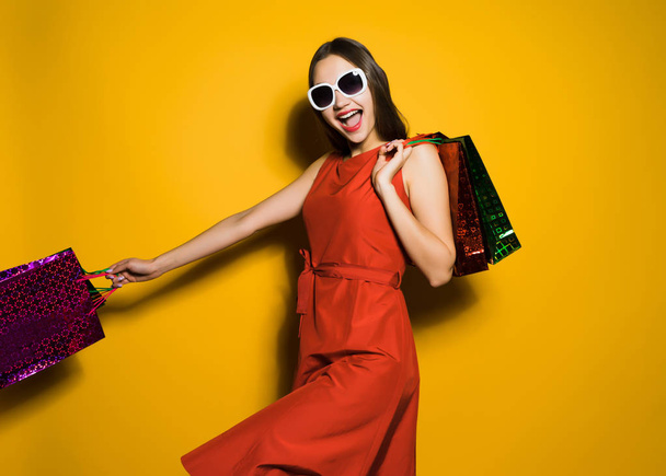 happy young girl in a red dress and sunglasses went shopping on a black Friday - Photo, Image