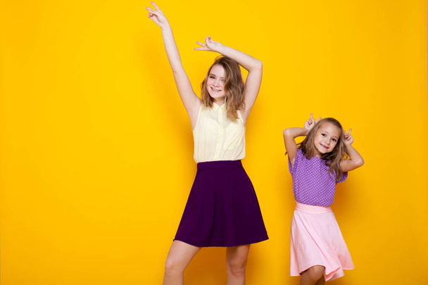 twee meisjes in gekleurde jurken lachen Toon vingers - Foto, afbeelding