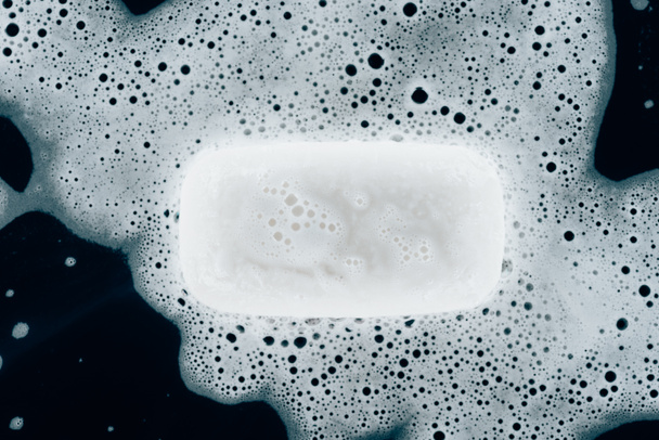 top view of white soap with foam on black table - Photo, Image