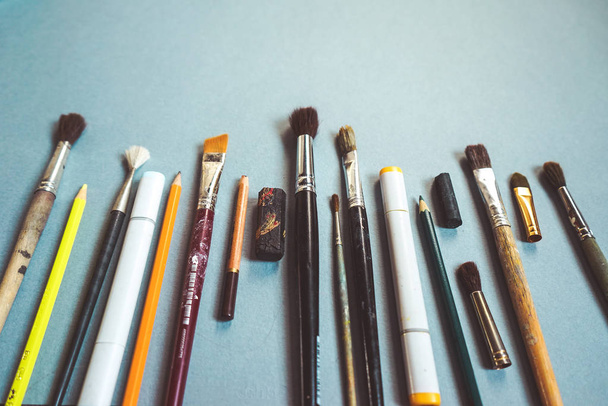 on a blue table lie art brushes and pencils - Φωτογραφία, εικόνα