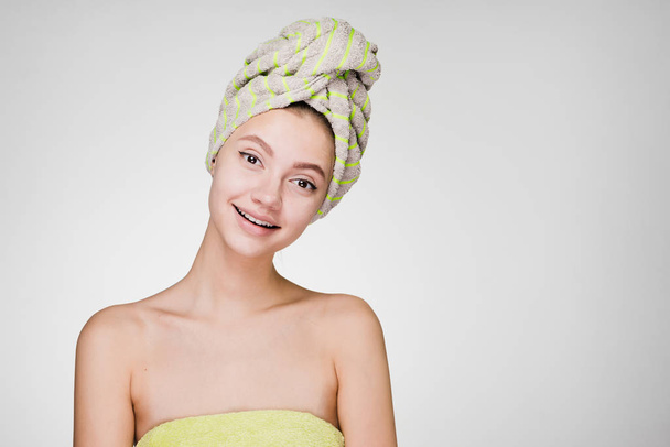 beautiful smiling girl with a towel on her head enjoying spa treatments - Фото, изображение