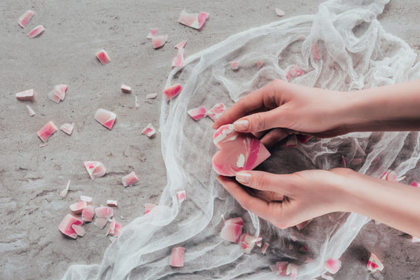 abgeschnittene Ansicht der Hände mit rosa Herzseife auf weißer Gaze auf Marmoroberfläche - Foto, Bild