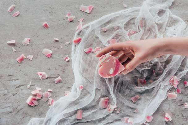обрізаний вид жіночої руки з рожевим милом у формі серця на білій марлі на мармуровій поверхні
 - Фото, зображення