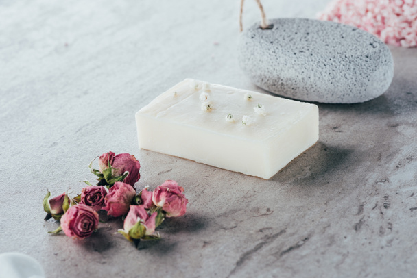 θεραπεία spa, αποξηραμένα τριαντάφυλλα, φυσικό σαπούνι και ελαφρόπετρα σε μαρμάρινη επιφάνεια - Φωτογραφία, εικόνα