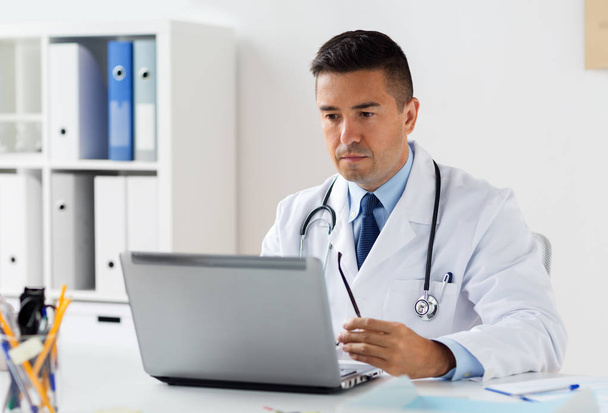 mannelijke arts in witte jas met laptop in ziekenhuis - Foto, afbeelding