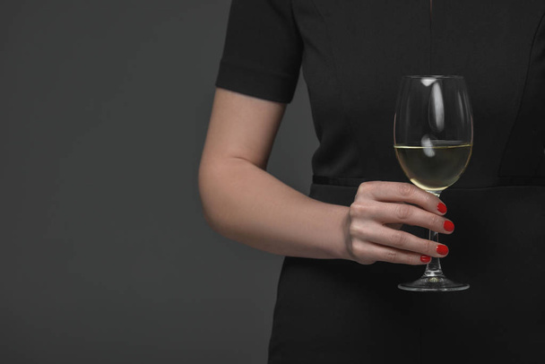 close-up partial view of woman in black dress holding glass of wine isolated on grey - Photo, Image