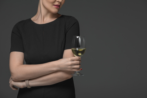 cropped shot of woman in black dress holding glass of white wine isolated on grey  - Фото, зображення