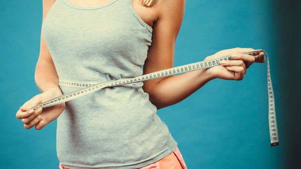 Fitness girl measuring her waistline - Foto, imagen