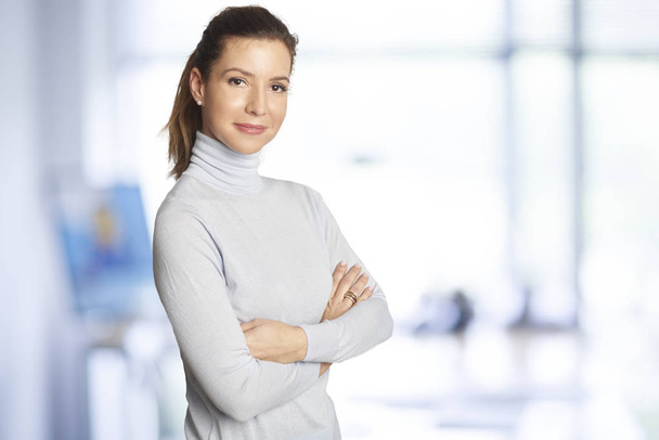 Executive sales businesswoman standing at the office with arms crossed and looking at camera. - Foto, Bild