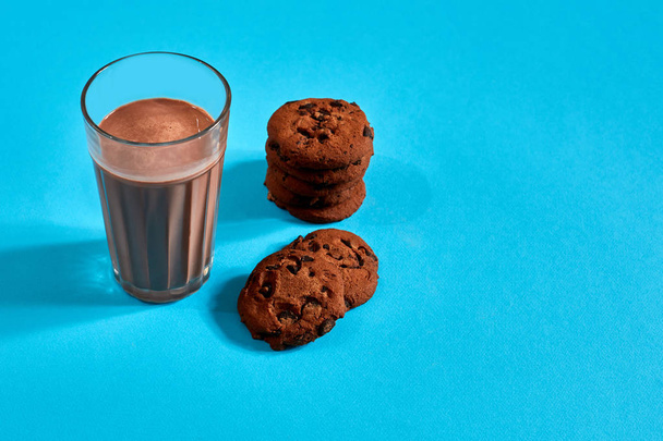 Schokoladenmilch mit Keksen auf blauem Hintergrund mit Platz für Text oder Design - Foto, Bild
