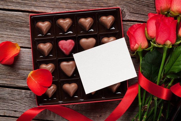 Carte de voeux Saint-Valentin avec roses rouges et chocolat en forme de coeur sur fond en bois. Vue du dessus
 - Photo, image