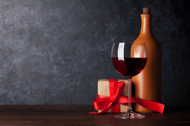 Valentines day greeting card with red wine bottle and gift box on wooden table in front of chalkboard.  - Photo, Image
