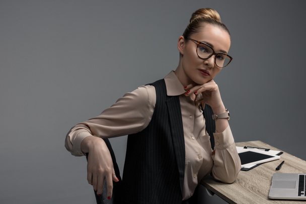 beautiful kazakh businesswoman in eyeglasses looking at camera isolated on grey - Foto, Imagen