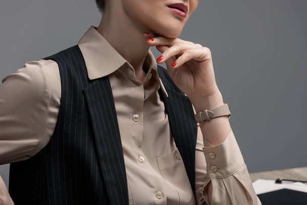 cropped shot of elegant kazakh businesswoman with hand on chin on grey - Foto, immagini