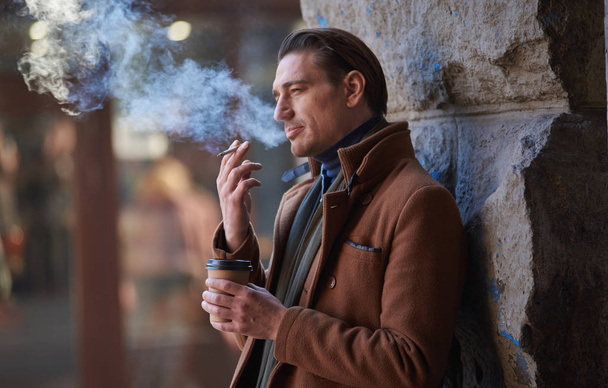 Serene man smoking cigarette outside - Foto, afbeelding