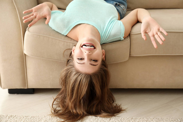 Beautiful smiling woman lying on sofa at home - 写真・画像