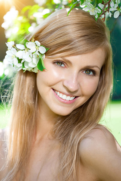 Young woman with a beautiful smile with healthy teeth with flowers. Face of a beautiful positive girl  Concept on the subject of dentistry, stomatology, dental care. - Фото, изображение