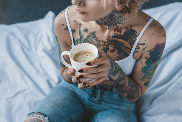 vágott nézet Tetovált lány rózsaszín haj kávét az ágyban reggel:  - Fotó, kép