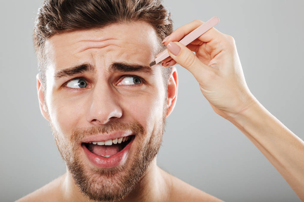 Female hand plucking scared men's eyebrows - Foto, immagini