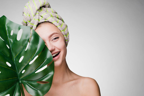 happy young girl with a towel on her head holds a green leaf, day spa - Foto, afbeelding
