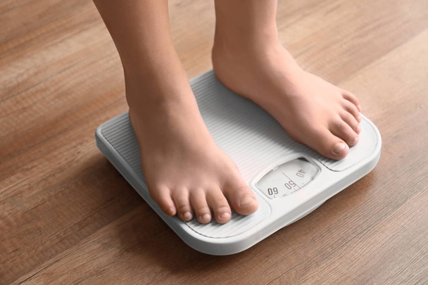 Overweight boy using scales  - Zdjęcie, obraz