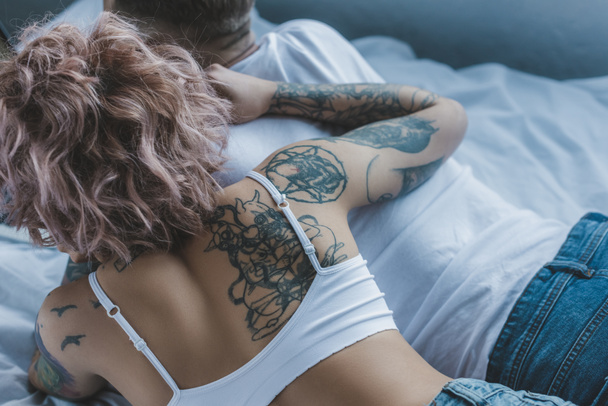 vista dall'alto della giovane coppia tatuata che si abbraccia a letto
 - Foto, immagini