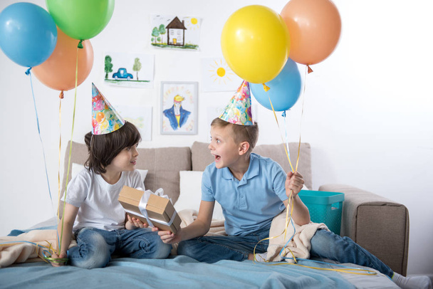 Pleased kids enjoying birthday party indoors - Foto, afbeelding