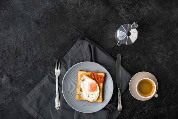 flat lay with cup of coffee and toast with fried egg and cherry tomatoes for breakfast on dark surface - Φωτογραφία, εικόνα