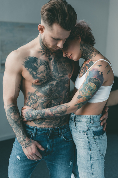 elegantes amantes tatuados abrazándose en el dormitorio
 - Foto, Imagen