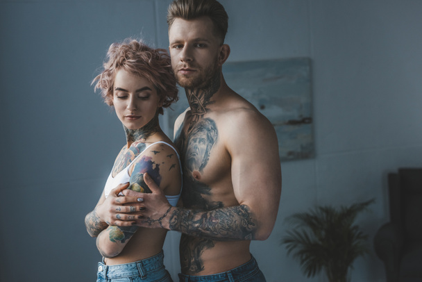 joven pareja tatuada abrazándose en el dormitorio
 - Foto, imagen