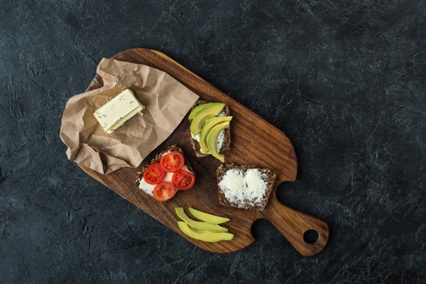 flat lay with snacks for healthy breakfast on wooden cutting board on dark tabletop - Foto, Imagen