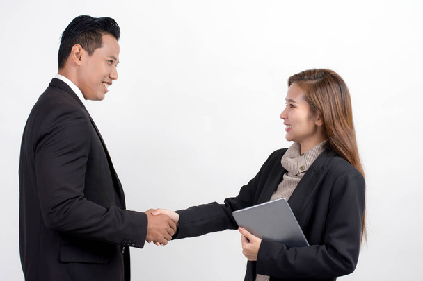 Porträt einer hübschen asiatischen Geschäftsfrau mit einem digitalen Tablet, die dem Geschäftsmann die Hand schüttelt, um einen Deal mit seinem Partner auf weißem Hintergrund zu besiegeln - Foto, Bild