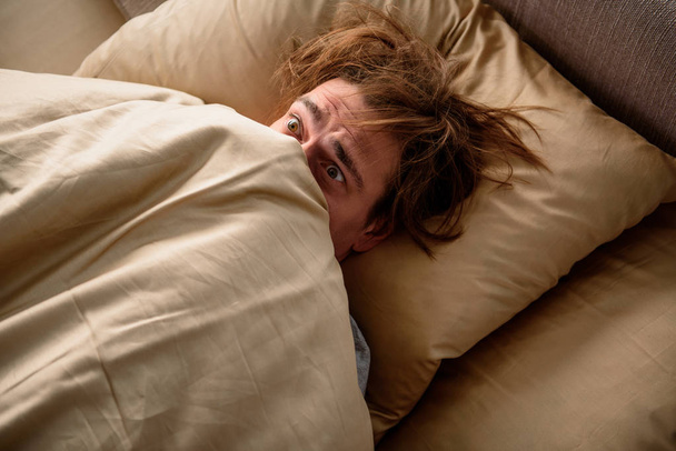 Panicked man unwilling to get up in the morning - Photo, image