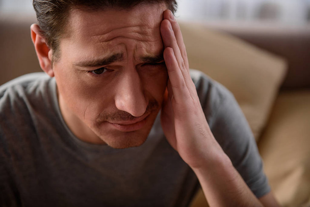 Tired adult male having a migraine at home - Foto, Imagen
