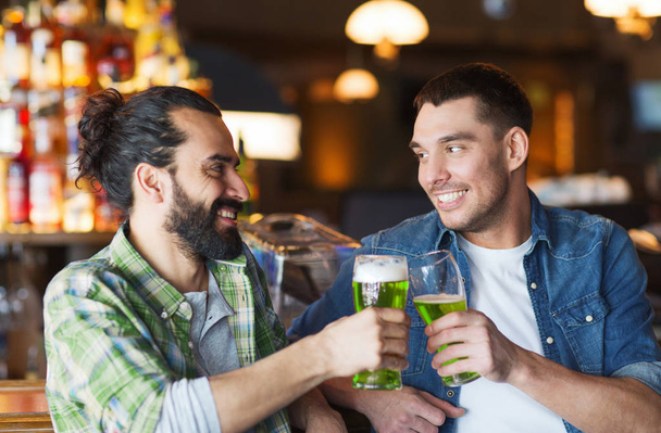 male friends drinking green beer at bar or pub - Фото, изображение