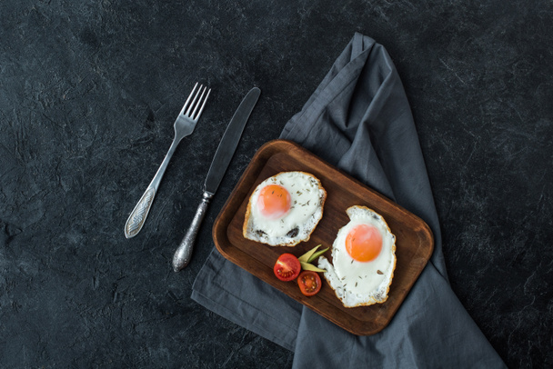 vista superior de ovos fritos com fatias de tomate cereja para o café da manhã em mesa escura
 - Foto, Imagem