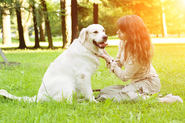 犬の訓練。公園で遊んで取得機能を持つ少女。背景にペットを歩いている女性の夏の風景。うれしそうな夏のシーン - 写真・画像
