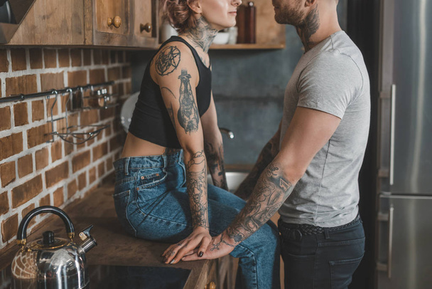 cropped view of young tattooed couple together in kitchen - Foto, immagini