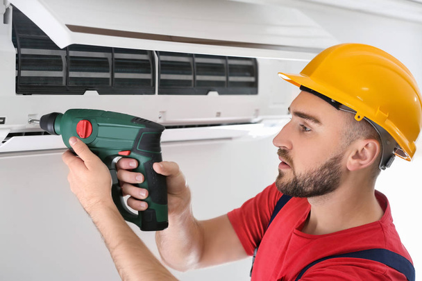 Male technician fixing air conditioner indoors - Foto, Imagen