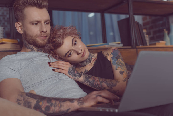 attractive caucasian couple relaxing and using laptop at home  - Foto, Imagen