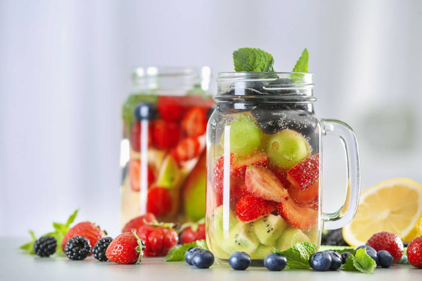 Mason jars of infused water with fruits and berries on table - Photo, Image