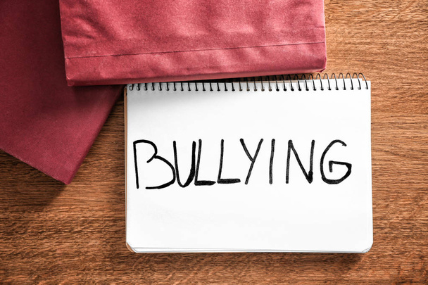 Notebook with word "Bullying" on wooden background - Valokuva, kuva