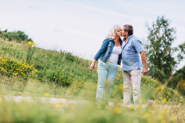Una pareja de ancianos besándose en un paseo. Actividades de jubilación de personas de edad avanzada
. - Foto, imagen