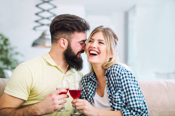 Фото молодой веселой пары, тостующей дома с вином
. - Фото, изображение