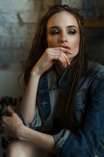 The beautiful girl topless wearing a jeans jacket touches her li - Fotografie, Obrázek