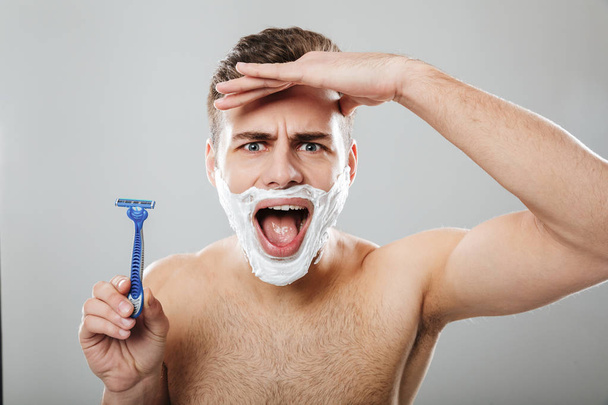 Funny facial expressions of unshaved male doing morning procedur - Fotografie, Obrázek